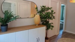 A hallway with a wooden console, a large mirror, and two potted plants.