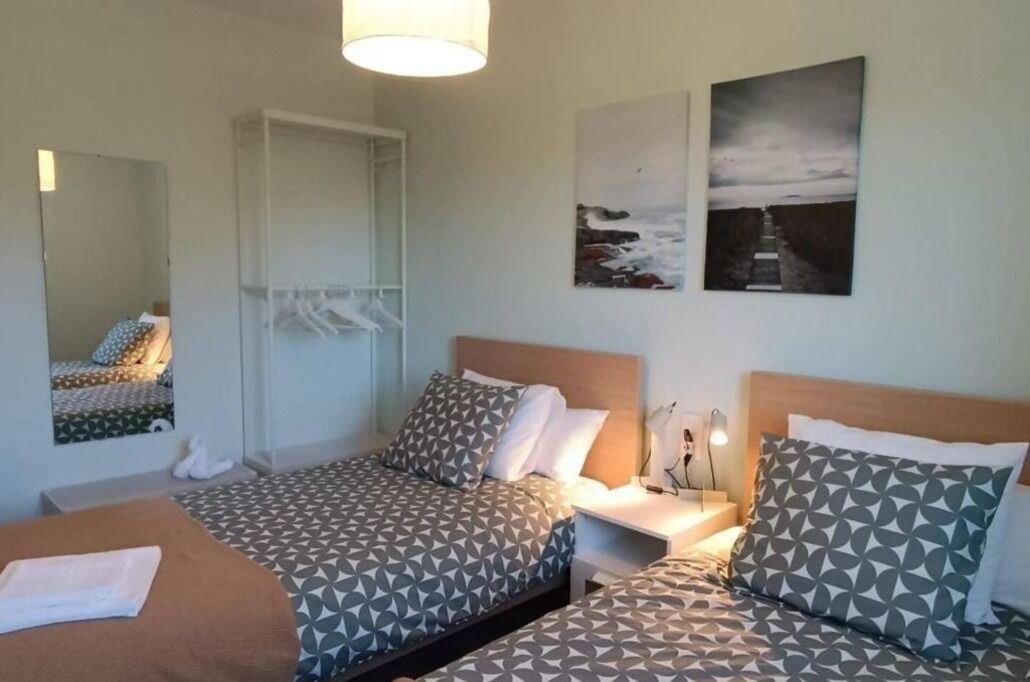 Een hotelkamer met twee bedden, een kast, een spiegel en kunstwerken aan de muur.