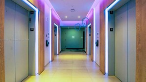 A modern hallway with elevators, marked with floor numbers, and illuminated by neon lights. - Private terrace above the Miami skyline: 1BR corner unit, 25th floor, Downtown Miami (Miami)
