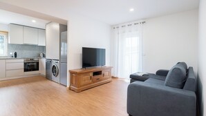 Ein modernes Wohnzimmer mit grauem Sofa und einem Flachbildfernseher auf einer Holzeinrichtung.