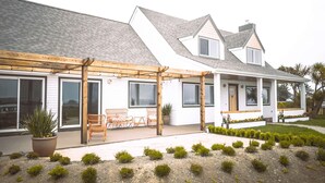 Une maison moderne à deux étages, dotée d’un patio couvert, de grandes fenêtres et d’un jardin bien entretenu.