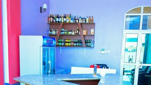 A bar area with a granite countertop, wooden stools, a refrigerator, and shelves with bottles. - MARKDON EXECUTIVE LODGE KISASA (Dodoma)