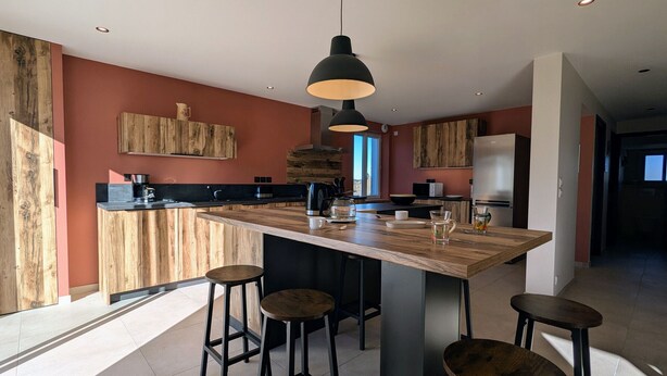 Una cocina moderna con una isla central, taburetes de bar e iluminación colgante.