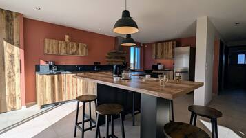 Een moderne keuken met een centraal eiland, barstoelen en hanglampen.