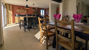 Una cocina moderna con una isla central, sillas de madera y una mesa de comedor preparada para cuatro.