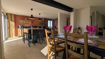 Een moderne keuken met een centraal eiland, houten stoelen en een eettafel gedekt voor vier personen.