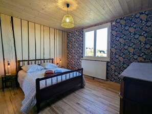 Un dormitorio con paneles de madera, una cama, un ventanal y un radiador.