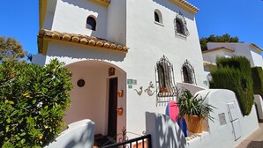 A white building with a yellow roof, a small entrance, and a sign indicating the address.