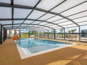 An indoor swimming pool with clear glass walls, surrounded by lounge chairs and a covered seating area. - 3-bedroom chalet with terrace in peaceful area of Saint-Romain-de-Benet (Saint-Romain-de-Benet)