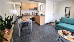 Un espacio habitable compacto con kitchenette, comedor y zona de estar con sofá.