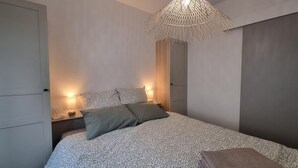 Un dormitorio con una colcha estampada, dos almohadas, una lámpara de noche y una lámpara colgante.