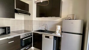 A modern kitchen with dark cabinetry, a built-in microwave, a stove, an oven, a dishwasher, a sink, and a refrigerator.