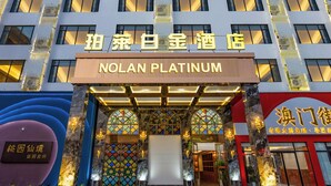 Entrada de hotel con un letrero que dice "Nolan Platinum" y otro letrero en un idioma diferente.