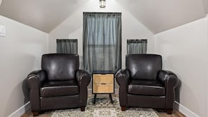 Una habitación con dos sillones de cuero, una mesita de madera y una alfombra estampada.
