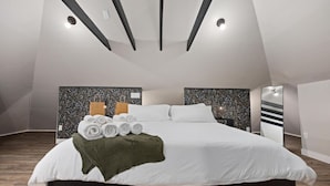 Un dormitorio moderno con una cama grande, un cabecero decorativo y un diseño de techo original.