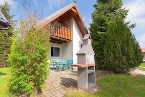 A house with a balcony, a stone fireplace, and a patio with outdoor furniture.