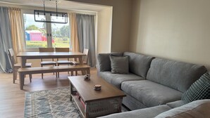 Un salon avec un canapé gris, une table basse en bois et une table à manger avec des chaises.