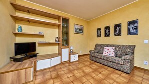 A living room with a TV, sofa, and wall-mounted shelves.