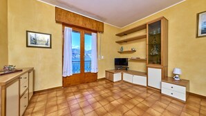 A compact living space with a balcony, a television, and a cabinet with glass doors.