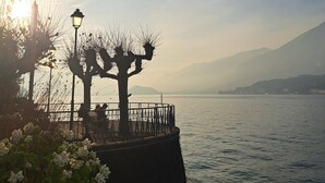 A waterfront promenade with benches and a lamp post, overlooking a calm lake with distant mountains. - Dinky's apartment with forest view balcony (Magreglio)