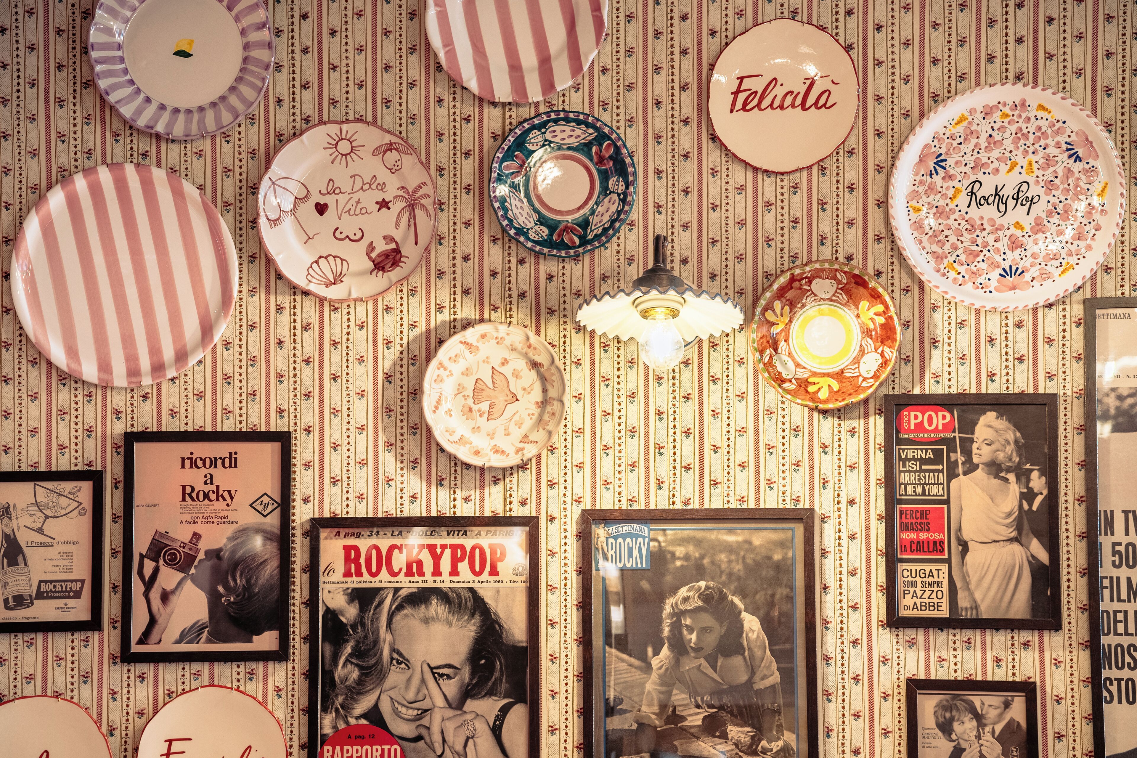 A wall with various framed items, including a poster with the word 'ROCKYPOP' and a framed photograph.
