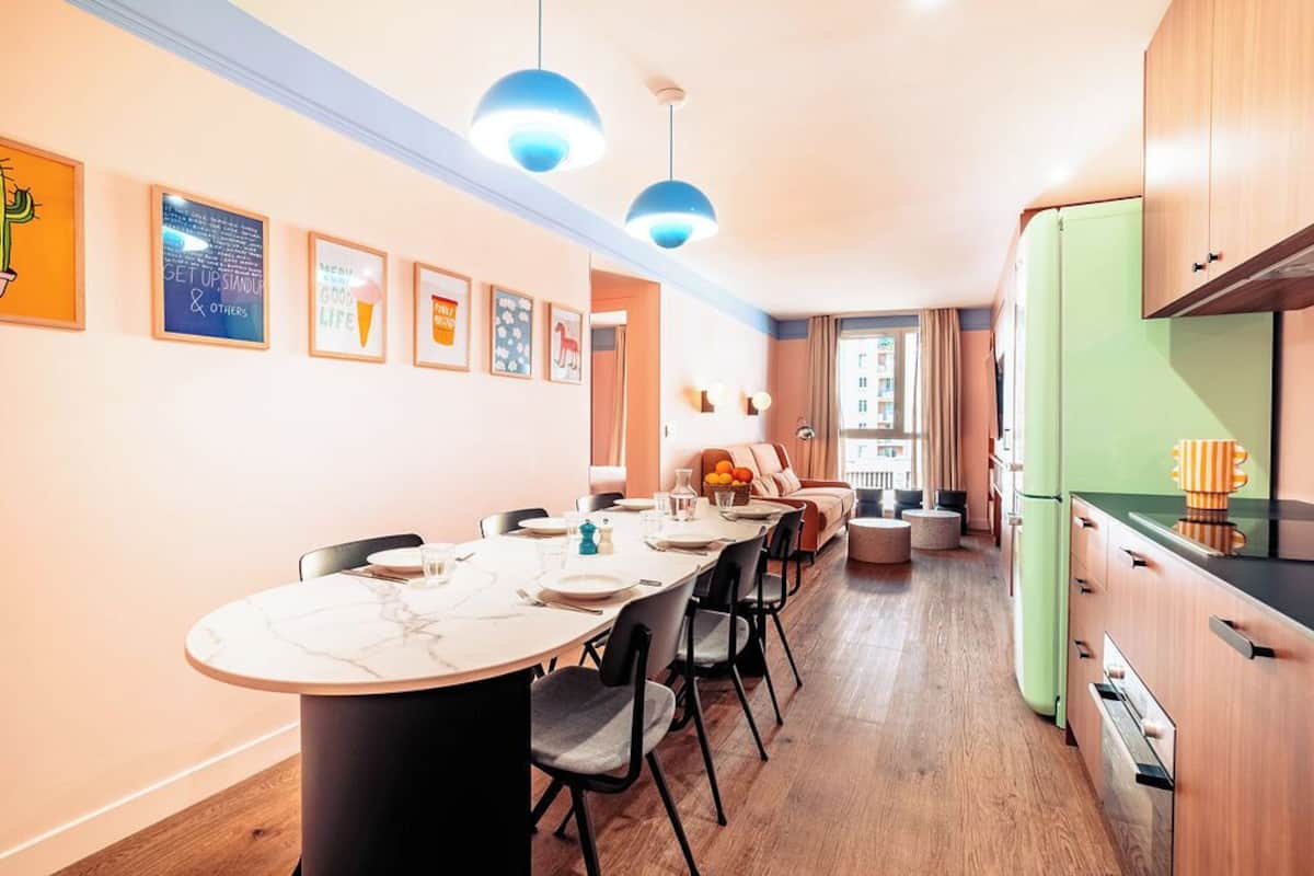 Une cuisine moderne avec un coin repas, des meubles en bois et des luminaires suspendus.