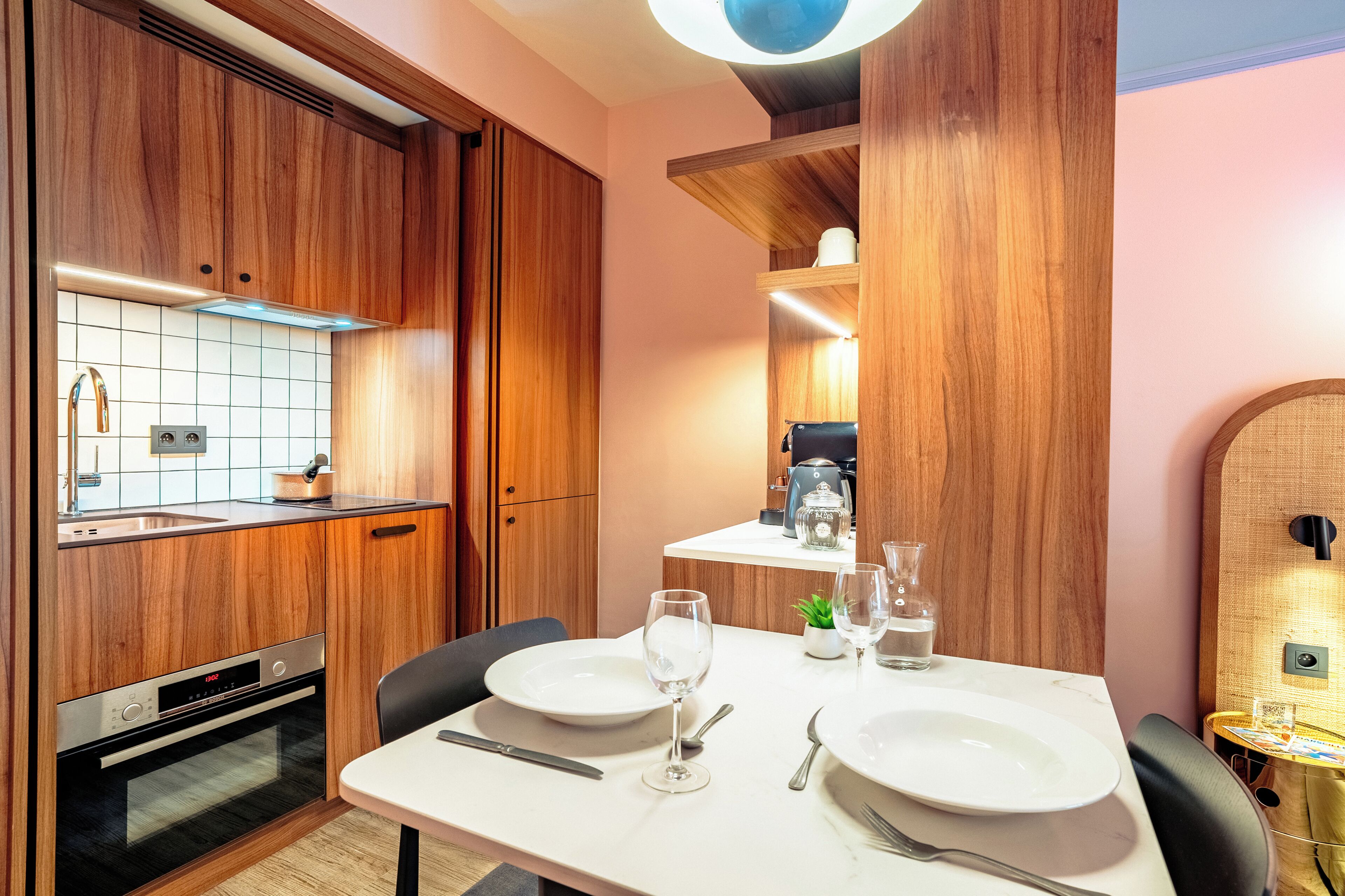 A compact kitchen with wooden cabinets, a built-in oven, and a dining area with a table set for two.