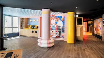 Un hall de hotel con mostrador de recepción, un cartel grande y suelo de madera.