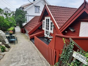 A red-roofed house with a white window and a small porch. There is a sign in front of the house that reads "STENG DARLIG KA!" - Fantastic fishing hut with sea view directly on the water (Korshamn)