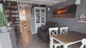 Een moderne keuken met witte kasten, een houten aanrecht en een ingebouwde oven. Er is een eethoek met een houten tafel en witte stoelen.