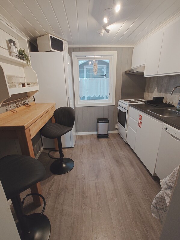 Cocina compacta con encimera de madera, estufa, fregadero y ventana con vistas al exterior.
