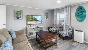 A living room with a sofa, a coffee table, a TV, and two patterned chairs.