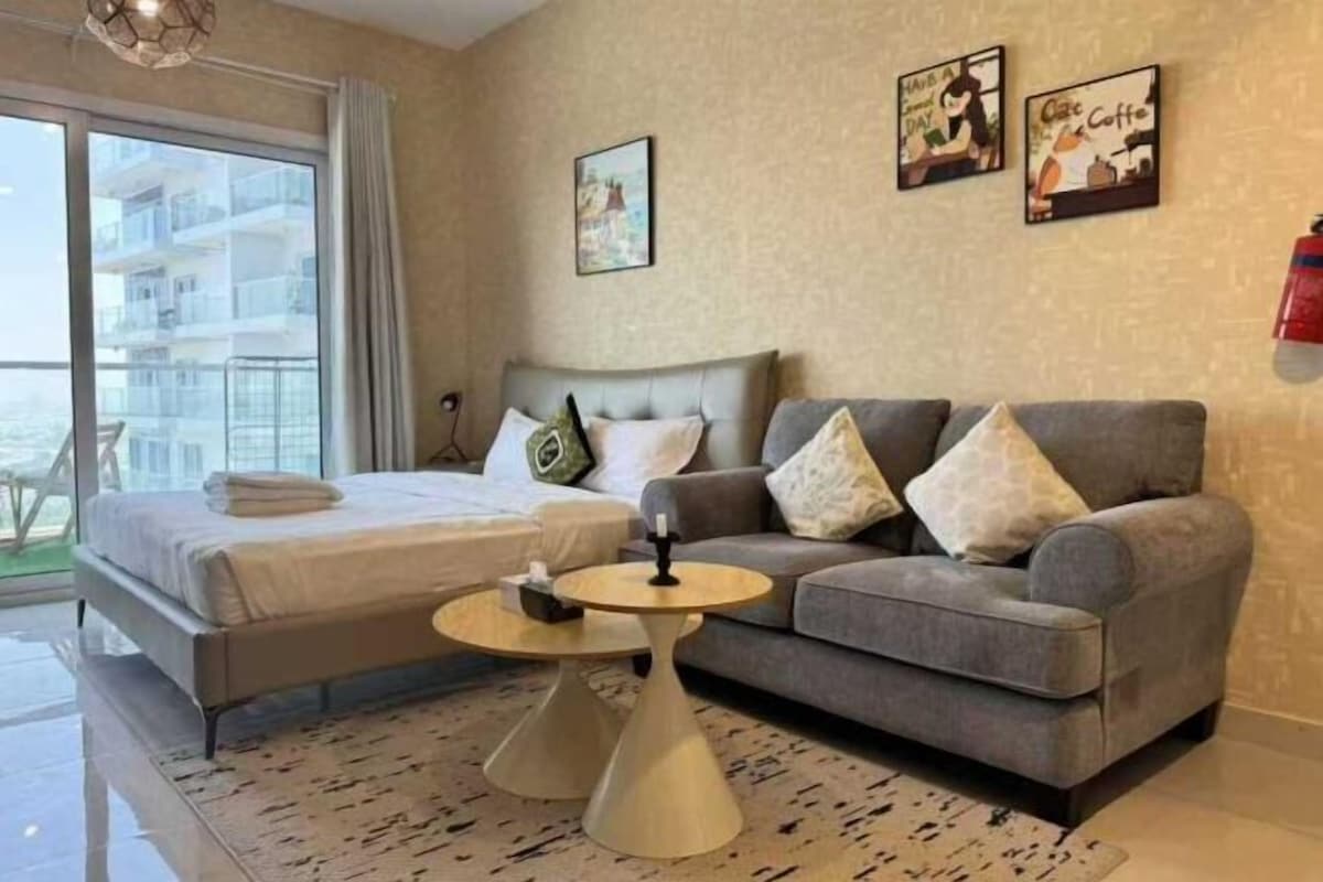 A hotel room with a bed, a sofa, a small table, and a view of the sea.