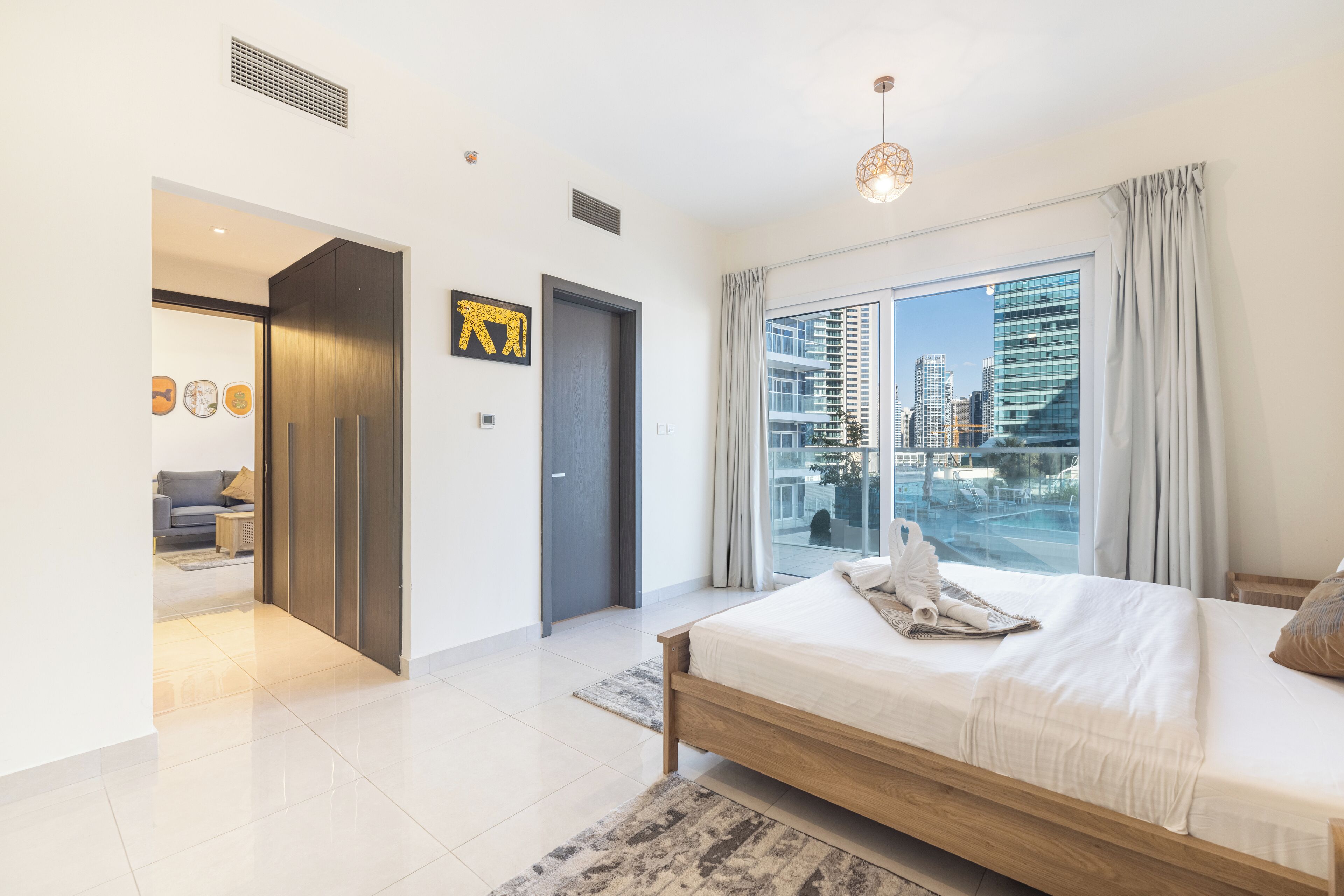 A modern bedroom with a large window, a bed, and a view of the city.