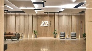 A modern lobby with a wooden wall, a reception desk, and seating area. - CaiCai Homes AG Tower Business Bay (Dubai)