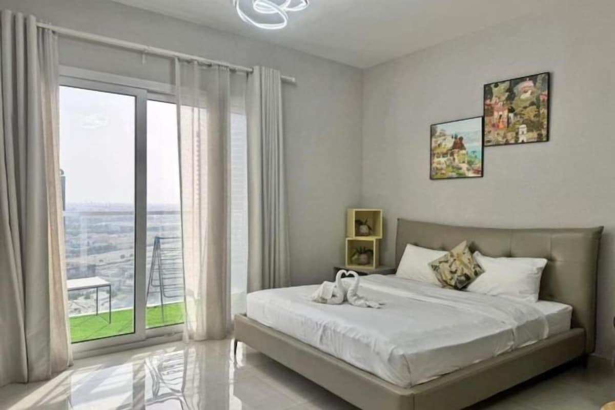 A bedroom with a large bed, a view through a sliding door, and two wall-mounted pictures.