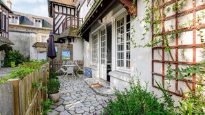 A courtyard with stone flooring, a wooden fence, and a building with a white facade and timber framing. - Romantic Stay, Isigny-sur-Mer (Isigny-sur-Mer)