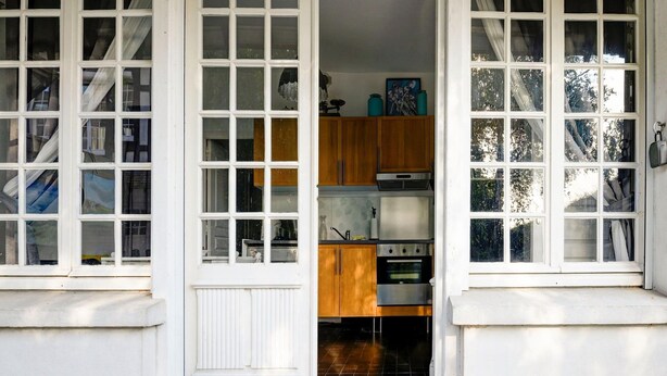 Una cocina con armarios blancos, estufa y piso de baldosas.