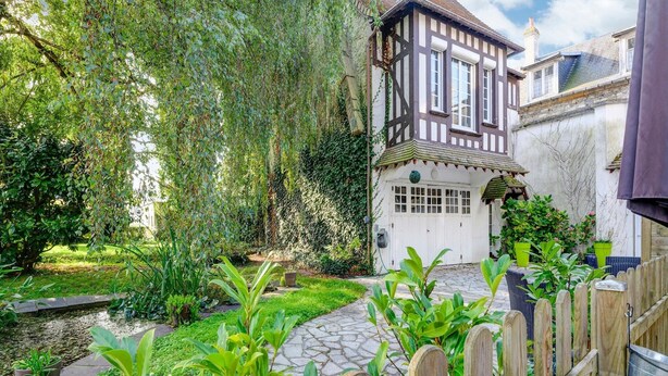 A traditional half-timbered house with a stone pathway leading to the entrance, surrounded by lush greenery and a wooden fence. - Romantic Stay, Isigny-sur-Mer (Isigny-sur-Mer)