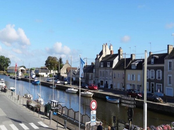 A waterfront street with buildings, a canal, and boats. - Romantic Stay, Isigny-sur-Mer (Isigny-sur-Mer)