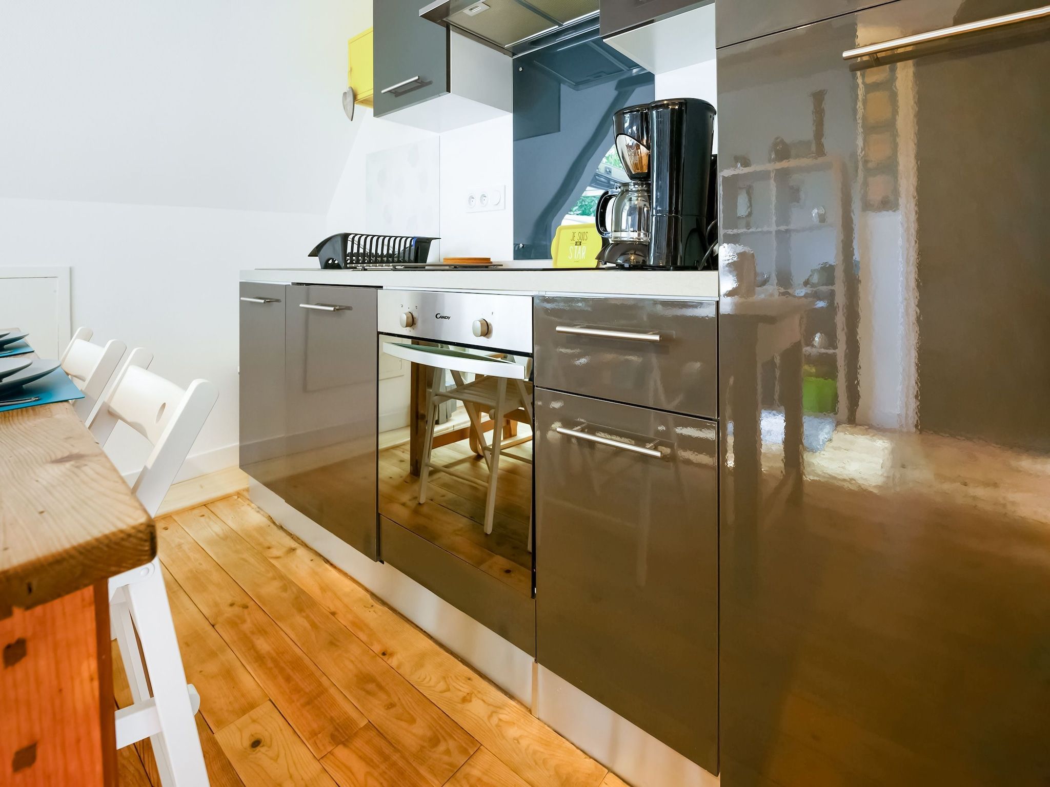 A modern kitchen with stainless steel appliances, a wooden dining table, and white chairs.