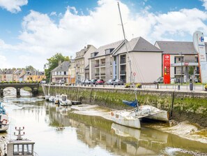 Een uitzicht op de rivier met een brug, boten en gebouwen, waaronder een markt en woonhuizen.