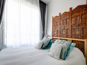 Een slaapkamer met een houten hoofdbord, een bed met witte lakens en twee kussens.