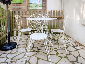 A patio with a stone-tiled floor, white metal chairs, and a table. - Romantic Stay, Isigny-sur-Mer (Isigny-sur-Mer)