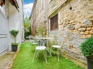 A courtyard with a stone wall, a white metal table and chairs, and a small tree. - Romantic Stay, Isigny-sur-Mer (Isigny-sur-Mer)