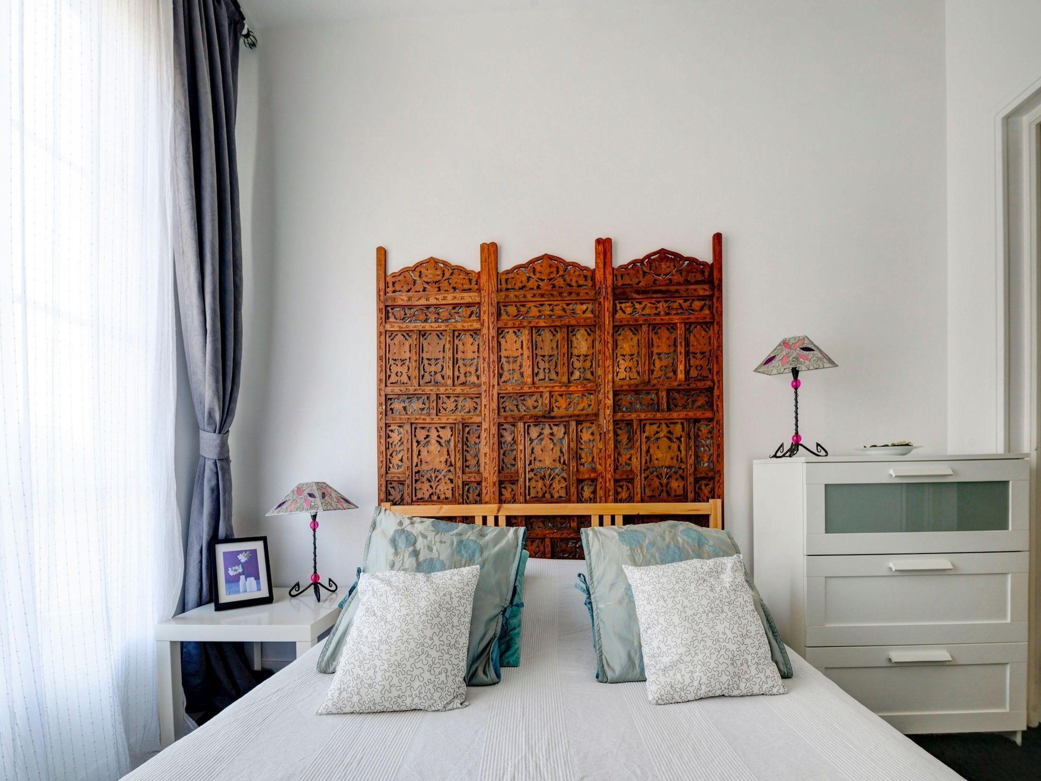 Une chambre à coucher comprenant un lit, une tête de lit, une table de chevet, une lampe et une commode.