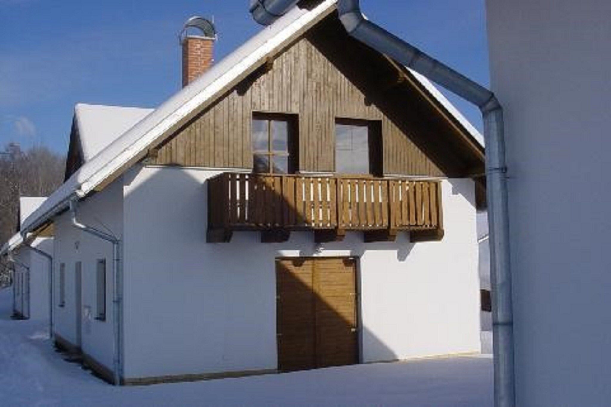Une maison à deux étages avec un balcon en bois et une cheminée.