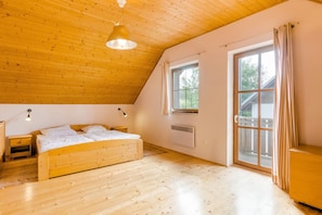 A bedroom with a wooden ceiling, a bed, a nightstand, a window, and a door.