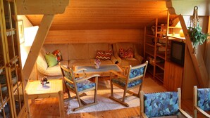 Un ambiente accogliente in legno, con soffitto a volta, divano, tavolo da pranzo e televisore.