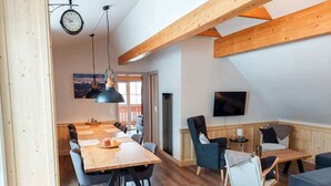 Un amplio salón con una mesa de comedor de madera, sillas, un televisor y un balcón.